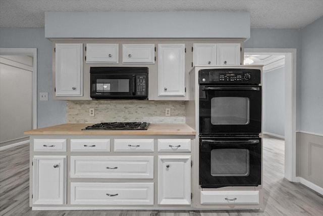 kitchen with tasteful backsplash, black appliances, a textured ceiling, light wood-type flooring, and white cabinets