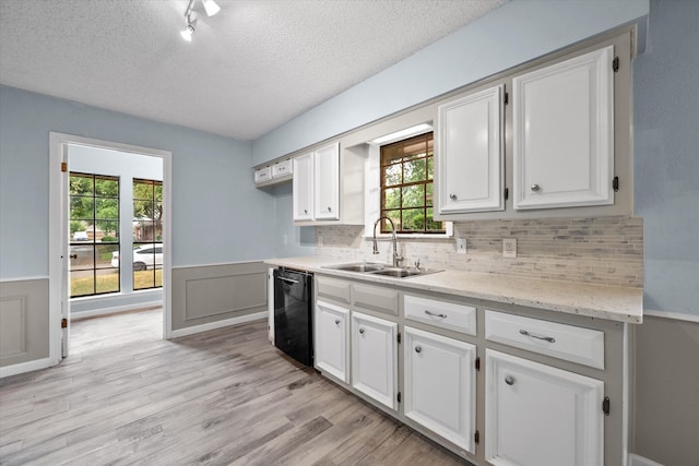 kitchen featuring black dishwasher, white cabinets, sink, and a textured ceiling