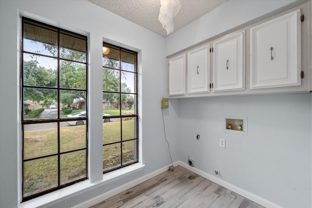 washroom featuring light hardwood / wood-style flooring, a textured ceiling, hookup for a washing machine, cabinets, and electric dryer hookup