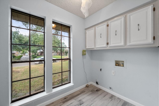 laundry room with cabinets, light hardwood / wood-style flooring, a textured ceiling, electric dryer hookup, and washer hookup