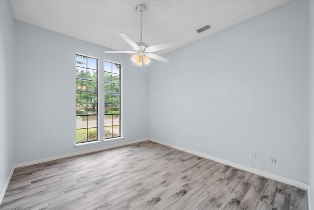 empty room with a textured ceiling, light wood-type flooring, and ceiling fan