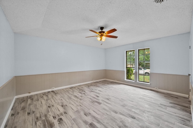 unfurnished room with ceiling fan, light hardwood / wood-style flooring, and a textured ceiling