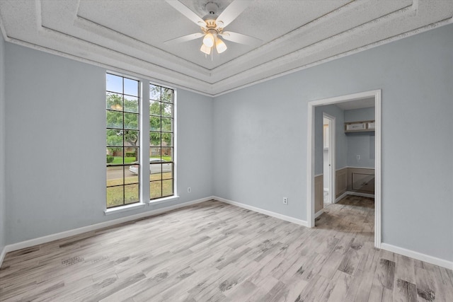 spare room with ceiling fan, a tray ceiling, light hardwood / wood-style floors, and a wealth of natural light