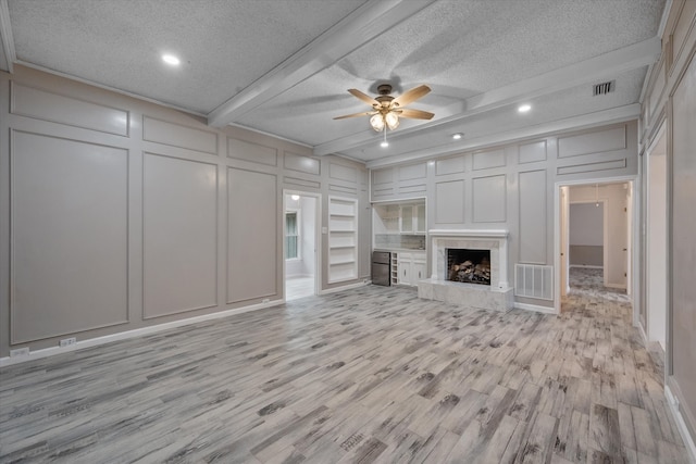 unfurnished living room with ceiling fan, light hardwood / wood-style floors, a high end fireplace, and a textured ceiling