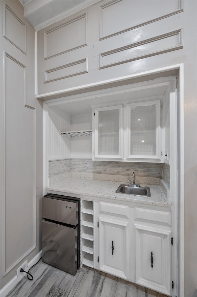 interior space featuring sink, light stone counters, fridge, light hardwood / wood-style floors, and white cabinetry