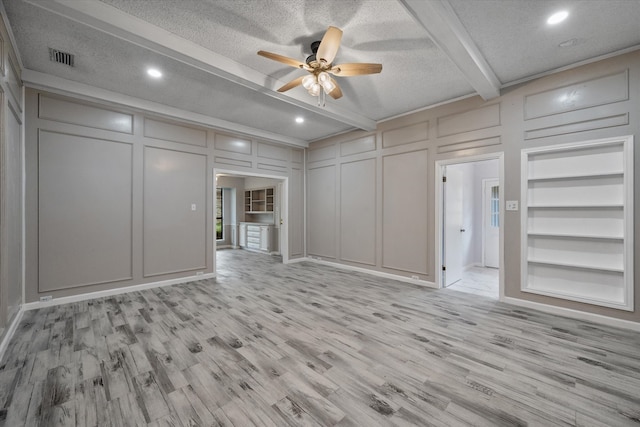 unfurnished living room with ceiling fan, beamed ceiling, light hardwood / wood-style floors, and a textured ceiling