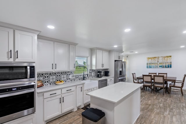 kitchen featuring white cabinets, stainless steel appliances, backsplash, and hardwood / wood-style floors