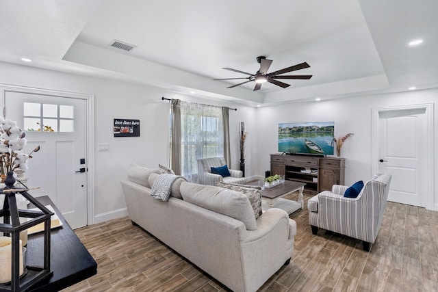 living room with ceiling fan, hardwood / wood-style flooring, and a tray ceiling