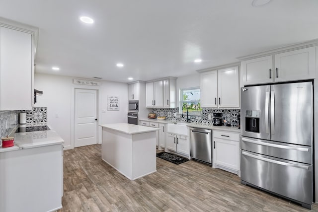 kitchen featuring white cabinetry, light hardwood / wood-style flooring, tasteful backsplash, a center island, and stainless steel appliances