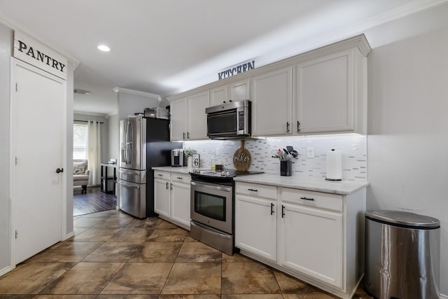 kitchen with white cabinetry, decorative backsplash, ornamental molding, and stainless steel appliances