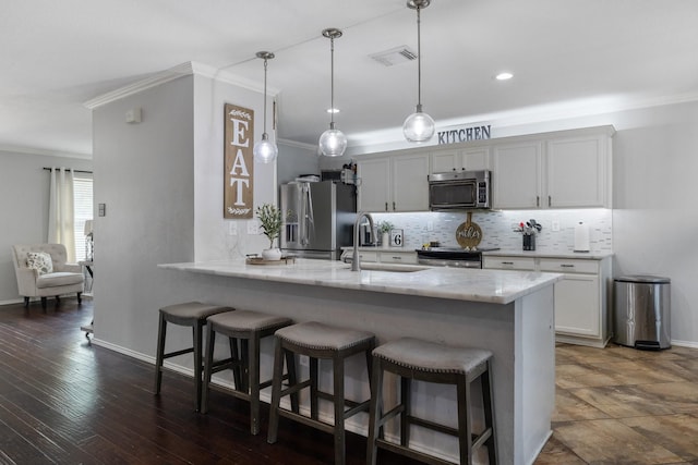 kitchen with decorative light fixtures, kitchen peninsula, stainless steel appliances, light stone countertops, and white cabinets