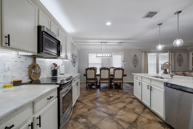 kitchen with appliances with stainless steel finishes, sink, pendant lighting, and white cabinets