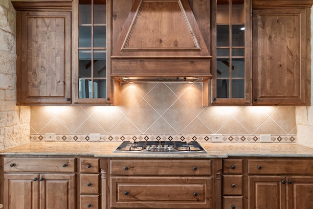 kitchen with tasteful backsplash, stainless steel gas stovetop, and light stone countertops