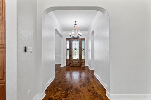 entryway with dark wood-type flooring, a notable chandelier, and ornamental molding