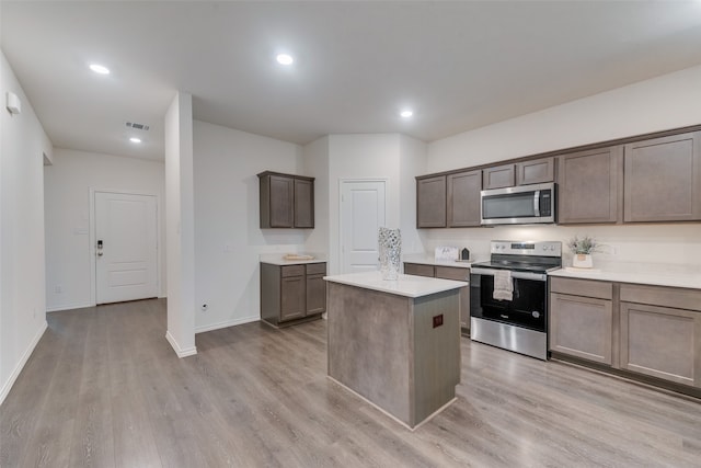 kitchen with a center island, dark brown cabinets, stainless steel appliances, and light hardwood / wood-style floors