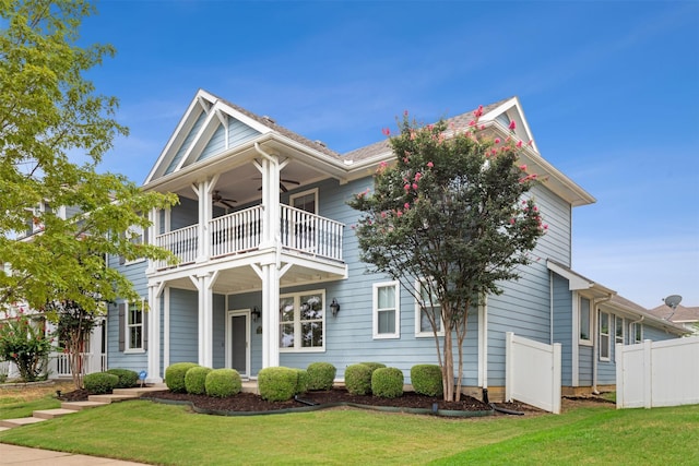 view of front facade with a balcony, ceiling fan, and a front lawn