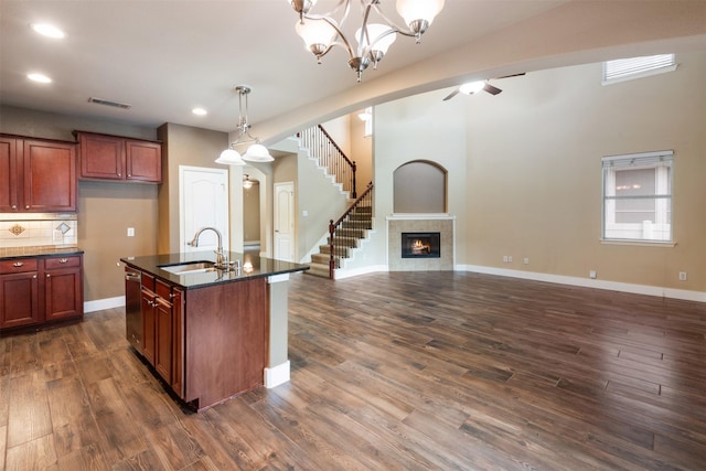 kitchen with dark hardwood / wood-style flooring, sink, pendant lighting, a center island with sink, and a fireplace