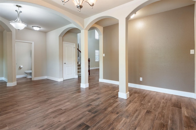 unfurnished room with dark wood-type flooring and an inviting chandelier