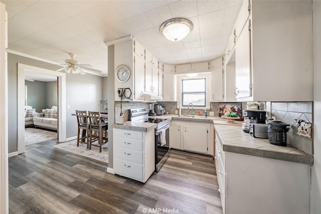 kitchen featuring sink, electric range, tile counters, white cabinets, and backsplash