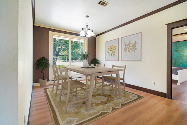 dining area with ornamental molding, a notable chandelier, and hardwood / wood-style floors