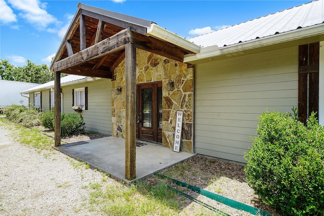 view of exterior entry featuring stone siding and metal roof