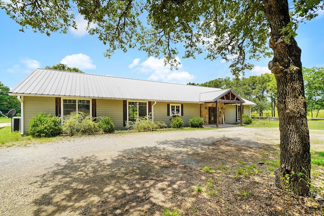 single story home featuring metal roof and driveway