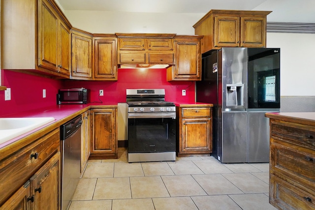 kitchen featuring light tile patterned floors, brown cabinetry, and stainless steel appliances