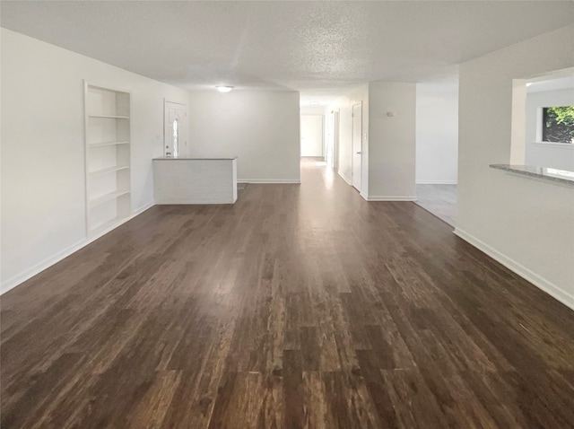 unfurnished living room featuring a textured ceiling, dark hardwood / wood-style flooring, and built in shelves