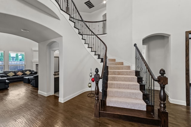 stairs featuring wood-type flooring, crown molding, and a towering ceiling