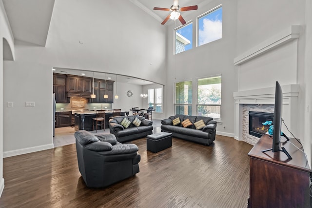 living room with ceiling fan, dark hardwood / wood-style floors, a high ceiling, and ornamental molding