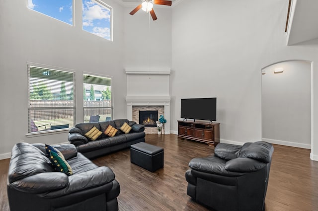 living room with dark wood-type flooring, a fireplace, a high ceiling, and ornamental molding