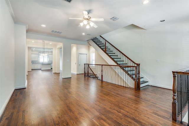 unfurnished living room featuring ceiling fan with notable chandelier, crown molding, and hardwood / wood-style floors