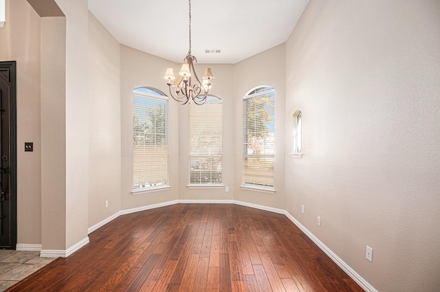 unfurnished dining area with hardwood / wood-style floors and a notable chandelier