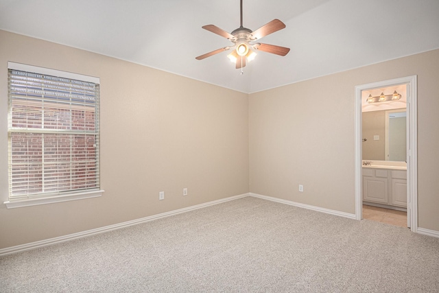 unfurnished bedroom with ceiling fan, light colored carpet, and ensuite bathroom