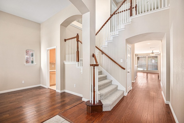 stairs featuring ceiling fan, a high ceiling, and hardwood / wood-style flooring