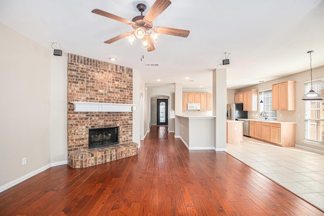 unfurnished living room with a fireplace, light wood-type flooring, and ceiling fan