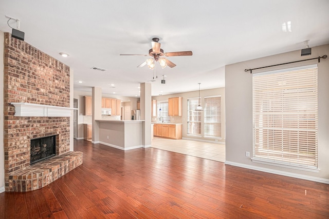 unfurnished living room featuring a fireplace, light hardwood / wood-style flooring, ceiling fan, and sink