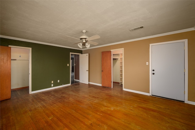 unfurnished bedroom with a closet, a spacious closet, wood-type flooring, and ceiling fan