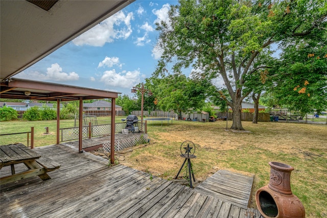 wooden terrace with area for grilling, a yard, and a shed