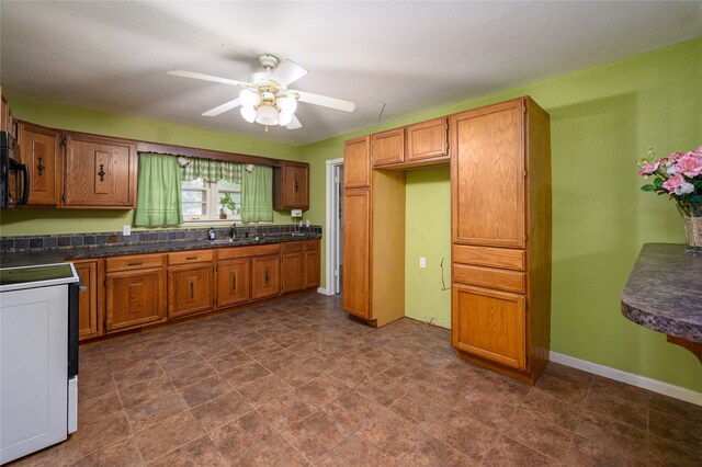 kitchen featuring sink, electric stove, ceiling fan, and dark tile patterned flooring