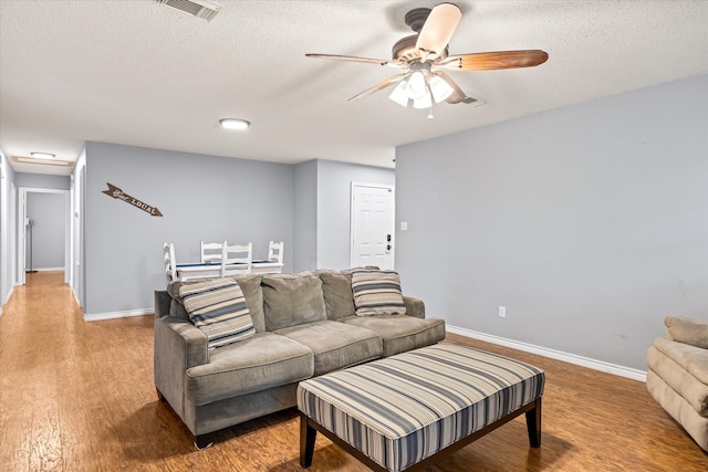 living room featuring a textured ceiling, hardwood / wood-style flooring, and ceiling fan