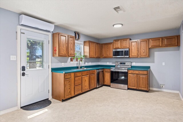 kitchen featuring a wall unit AC, appliances with stainless steel finishes, light tile patterned floors, and sink