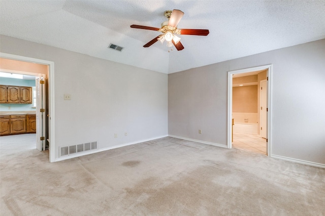 carpeted empty room featuring a textured ceiling, vaulted ceiling, and ceiling fan