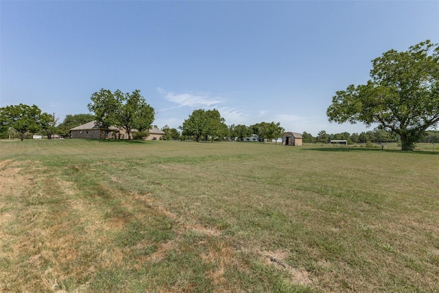 view of yard with a rural view and a storage shed