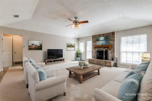 carpeted living room with lofted ceiling, ceiling fan, a textured ceiling, and a brick fireplace