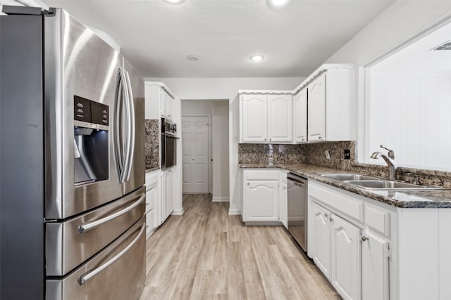 kitchen with sink, white cabinets, backsplash, light hardwood / wood-style floors, and stainless steel appliances