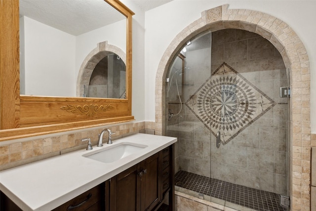 bathroom with an enclosed shower, vanity, tasteful backsplash, and a textured ceiling