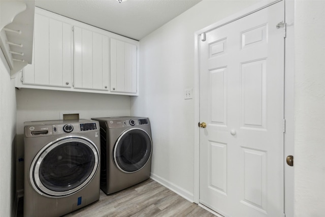 washroom featuring cabinets, light hardwood / wood-style floors, and washer and dryer