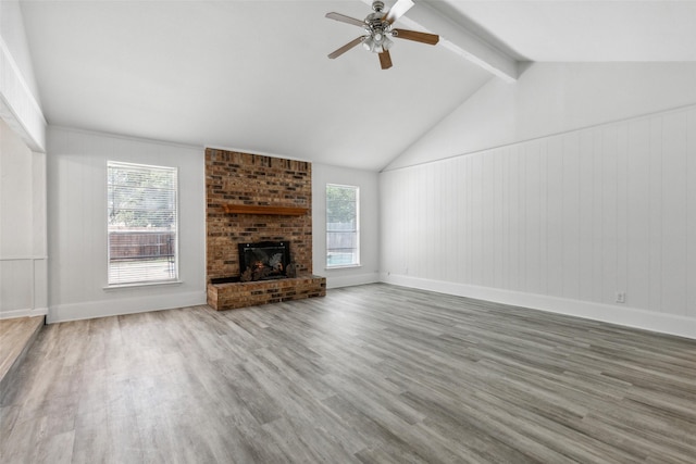 unfurnished living room with hardwood / wood-style flooring, a brick fireplace, and a wealth of natural light