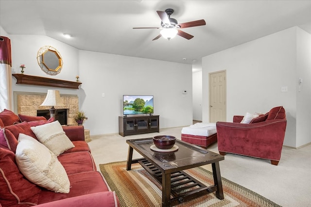 carpeted living room with a stone fireplace, ceiling fan, and vaulted ceiling